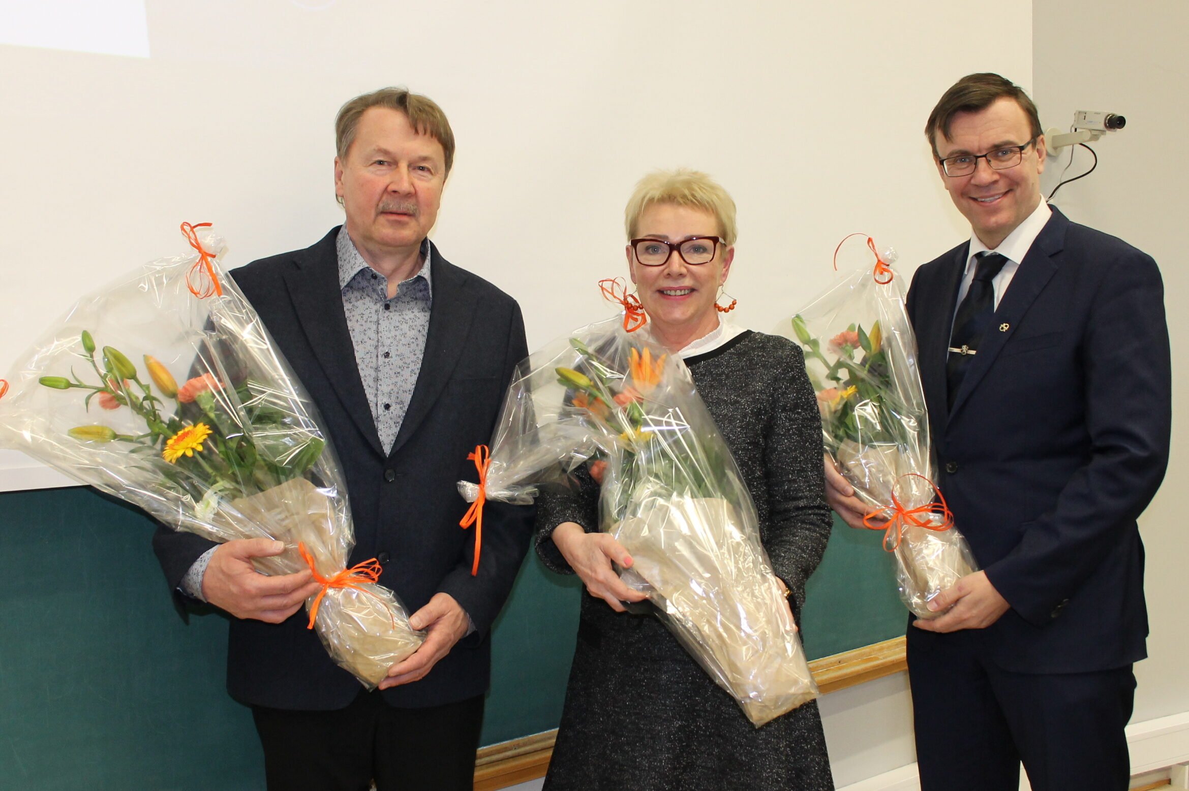 Kuvassa kukkakimppujen kera aluevaltuuston puheenjohtajisto vasemmalta lukien Lassi Valkeapää, Eeva Arvela ja Ilpo Heltimoinen.