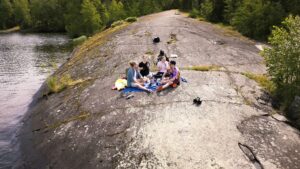 Neljä nuorta ovat piknikillä kalliolla. Kuvassa näkyy, että ilma on lämmin.