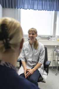 Lääkäri juttelee sairaanhoitajan kanssa ja hymyilee