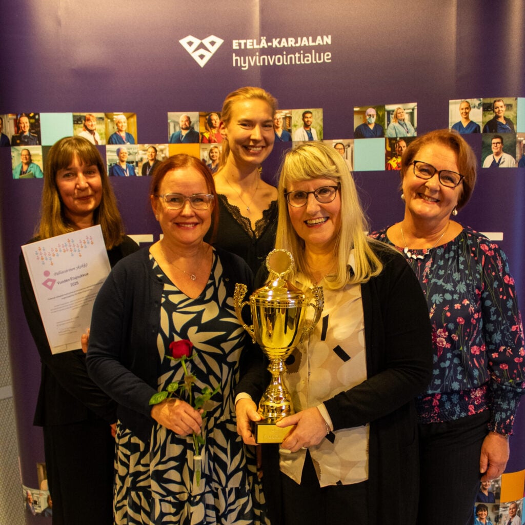 Viisi palliatiivisen yksikön edustajaa kuvattuna pokaalin kanssa.