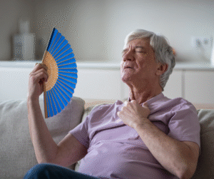 vanhempi mies istuu sohvalla ja heiluttaa viuhkaa