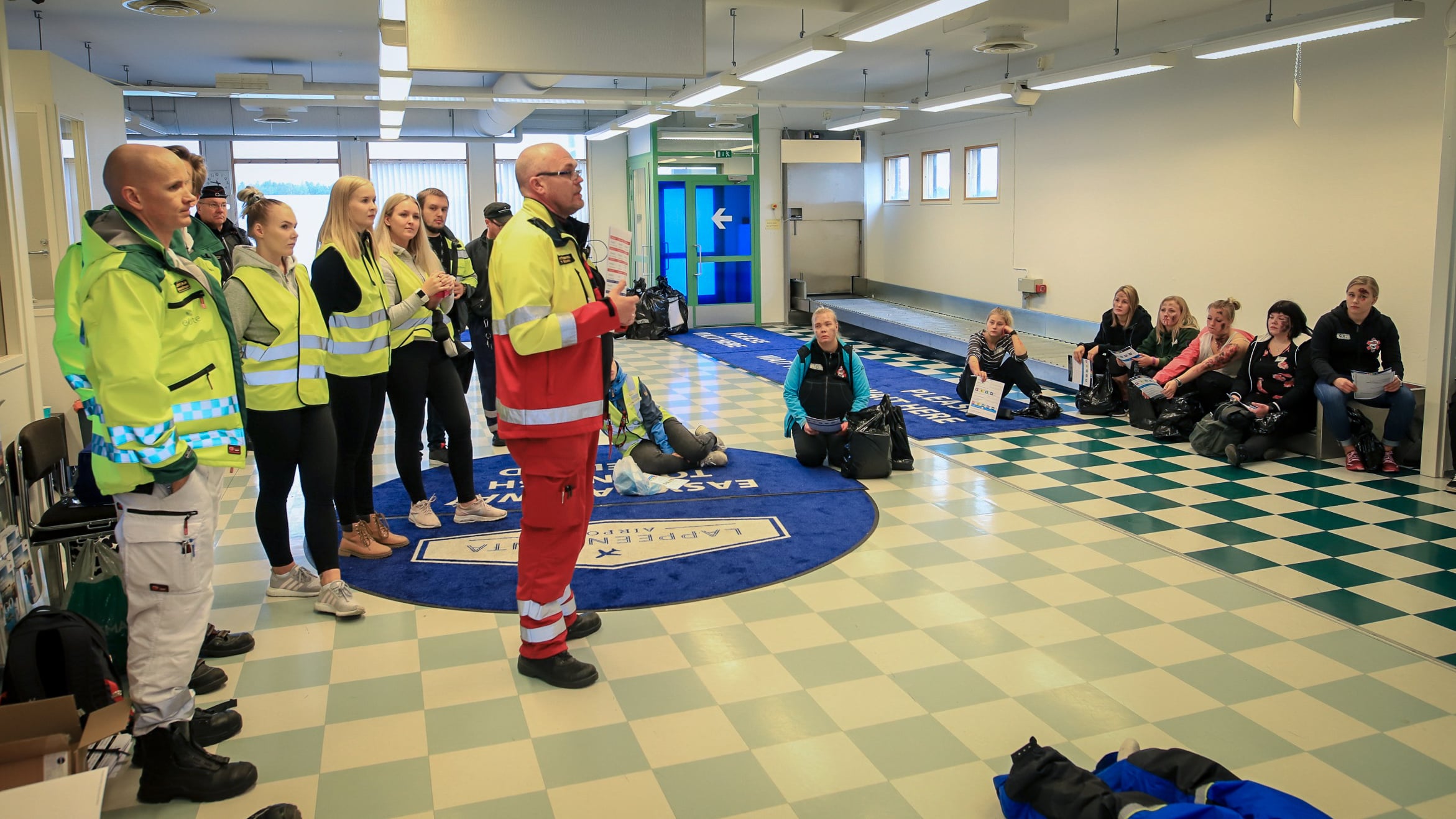 Harjoitustilanne, jossa ensihoitajia, pelastajia ja vapaaehtoisia nuoria keskustelemassa.